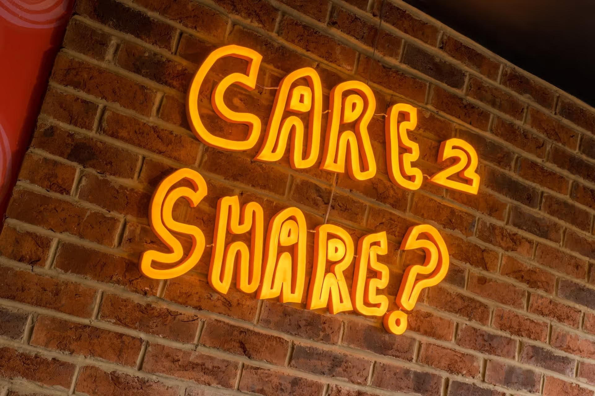 Neon sign which says "Care 2 Share?" at Zizzi Reading