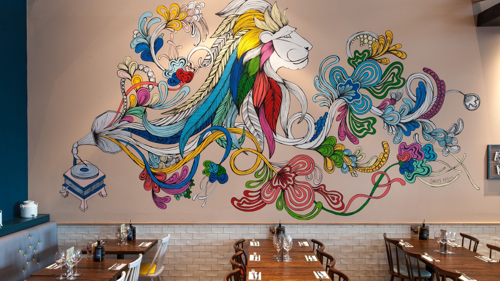 Tables and chairs with art wall Zizzi Wembley. 