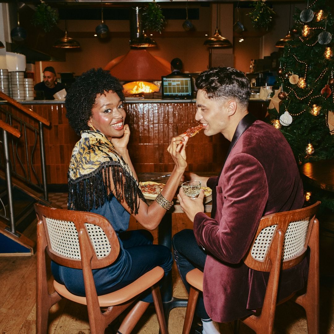 A couple feeding pizza to each other 