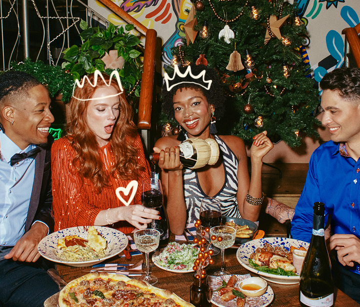 Friends celebrating Christmas at the table with food and drink 