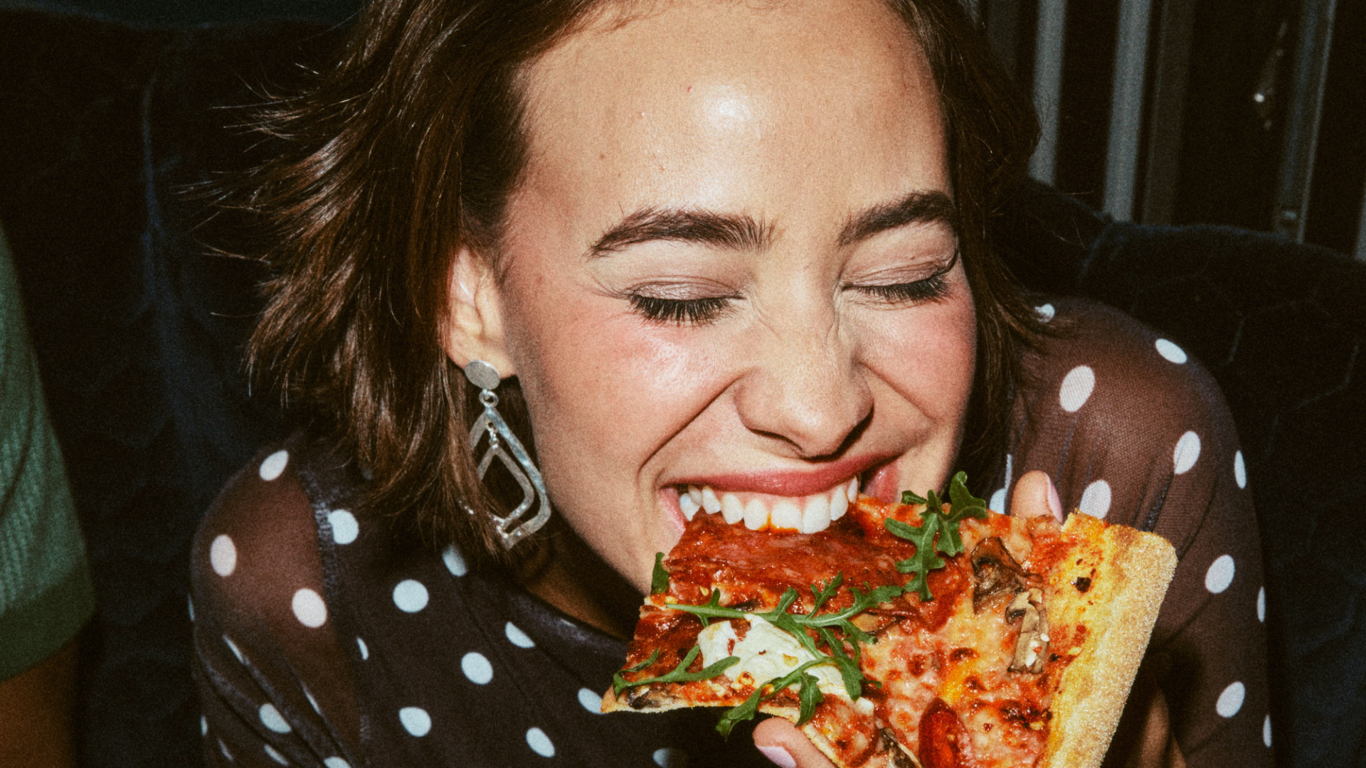 Woman biting into a slice of pizza 
