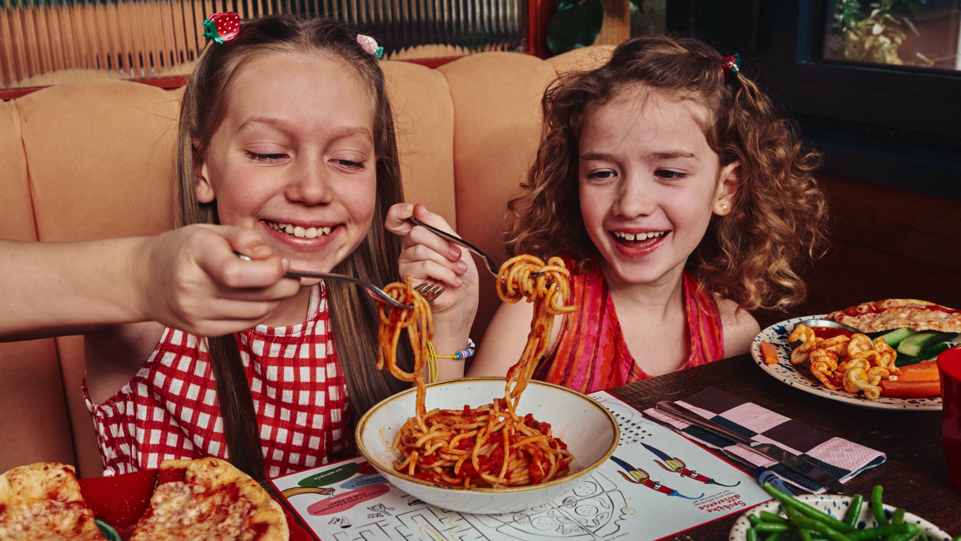 Two children eating pasta